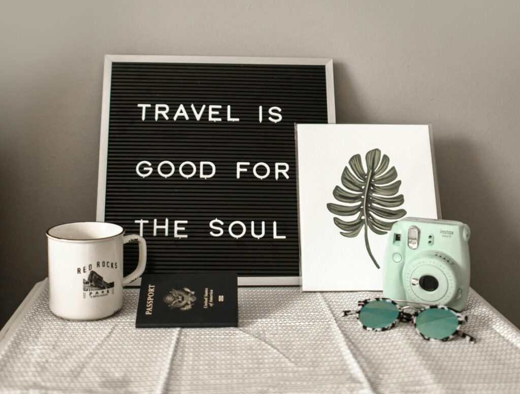 A travel-themed flat lay with a camera, coffee, and motivational quote.